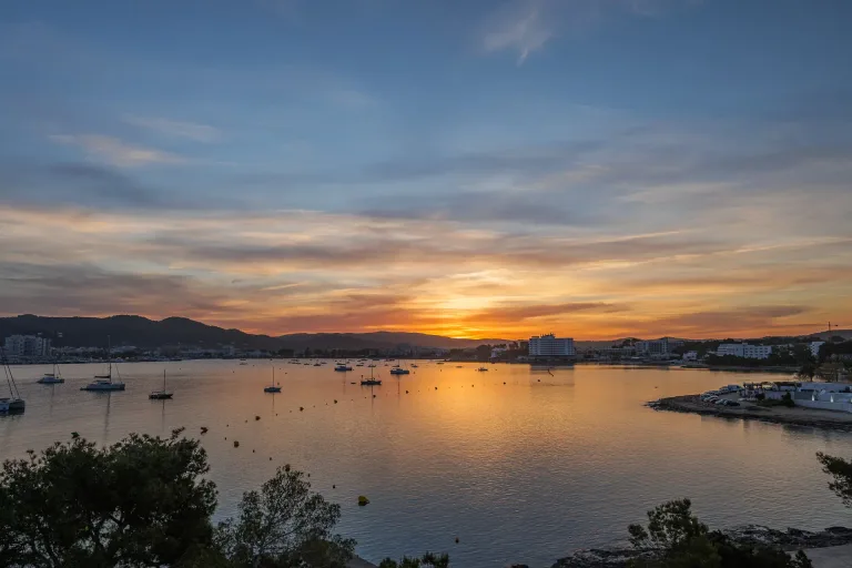 vista del amanecer de una bahia con barcos en ibiza
