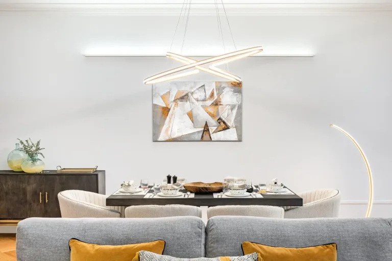 vista frontal de un sofa con almohadas una mesa de comedor con cubiertos y una pintura abstracta en la pared