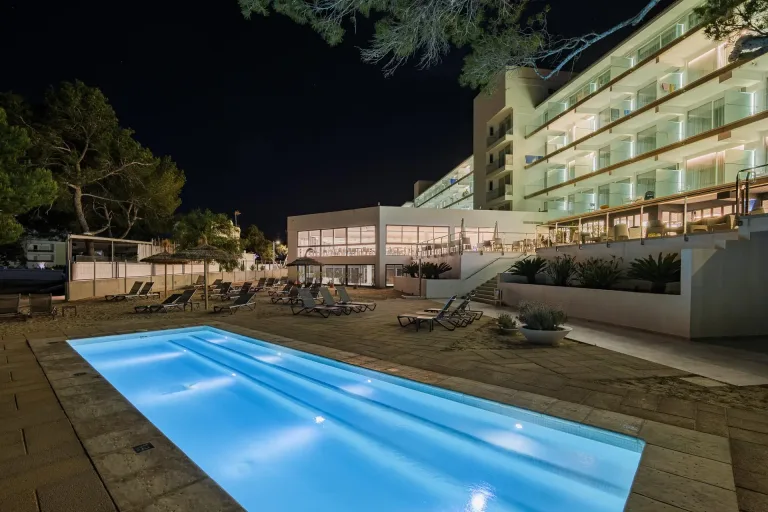 vista nocturna de una piscina con tumbonas y un hotel al fondo fotografia exterior ibiza
