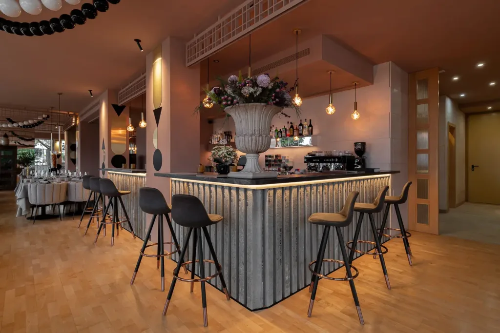 Barra de bar elegante con taburetes altos y gran florero