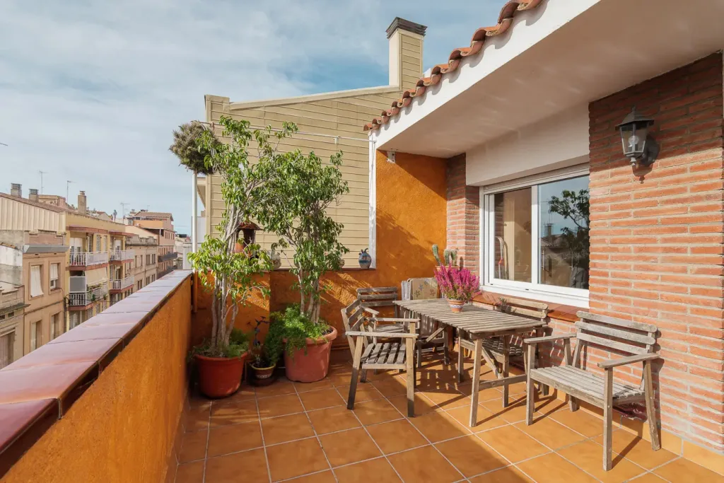 Terraza soleada con mobiliario de madera y plantas