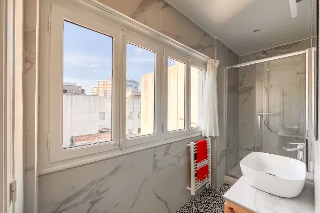 bano con azulejos imitacion marmol y ducha de cristal