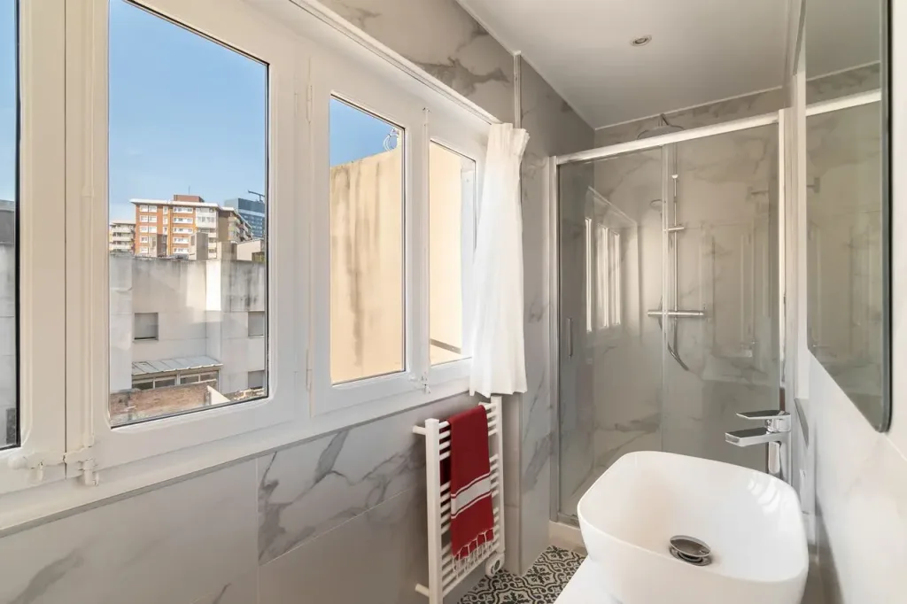 baño luminoso con ducha y azulejos de marmol