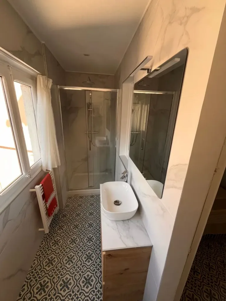 baño estrecho con encimera de mármol y azulejos estampados