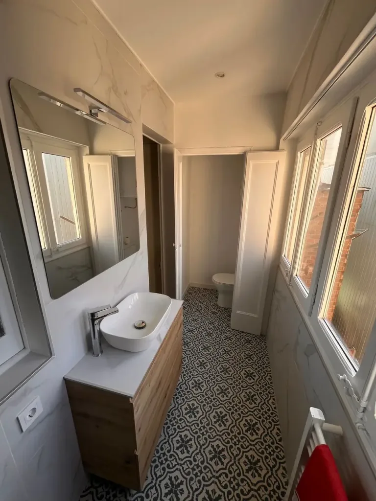 baño luminoso con ducha de vidrio y azulejos decorativos en el suelo