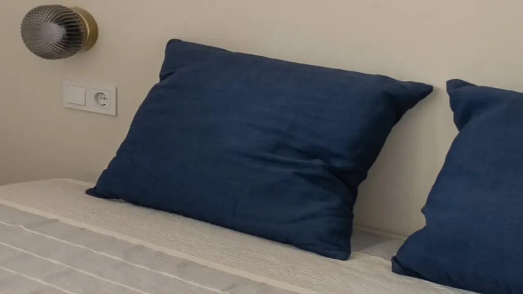 detalle de almohadas azules oscuras en cama con colcha a rayas