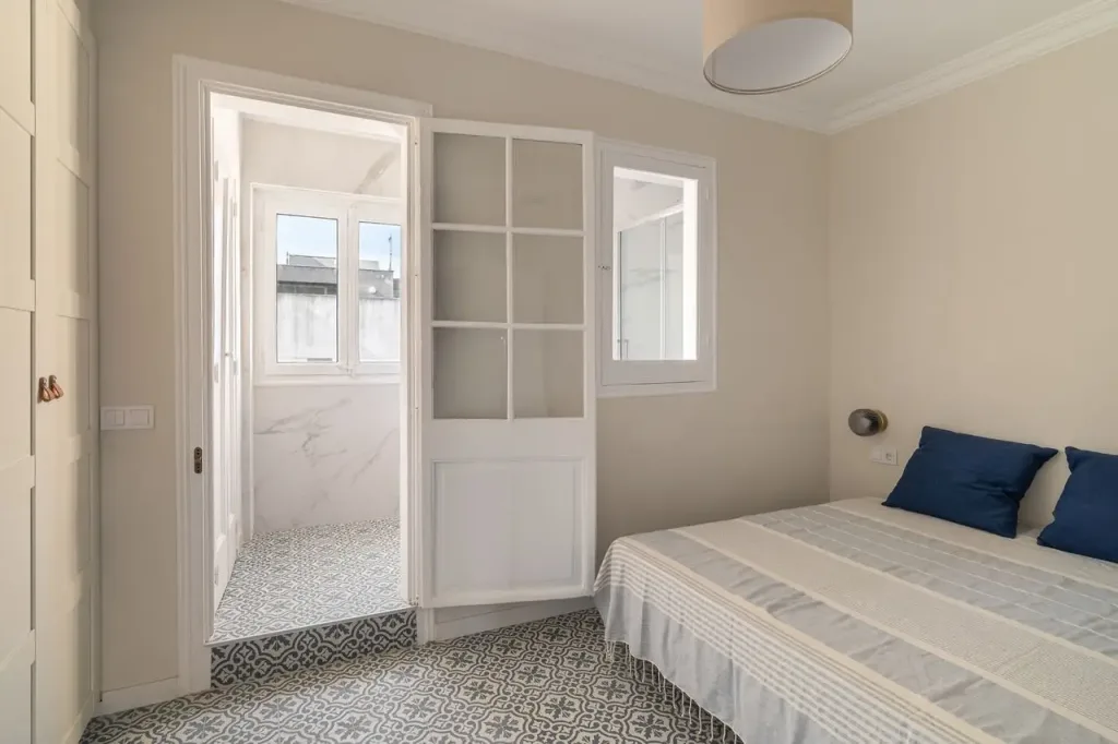 dormitorio luminoso con cama doble y suelo de mosaico