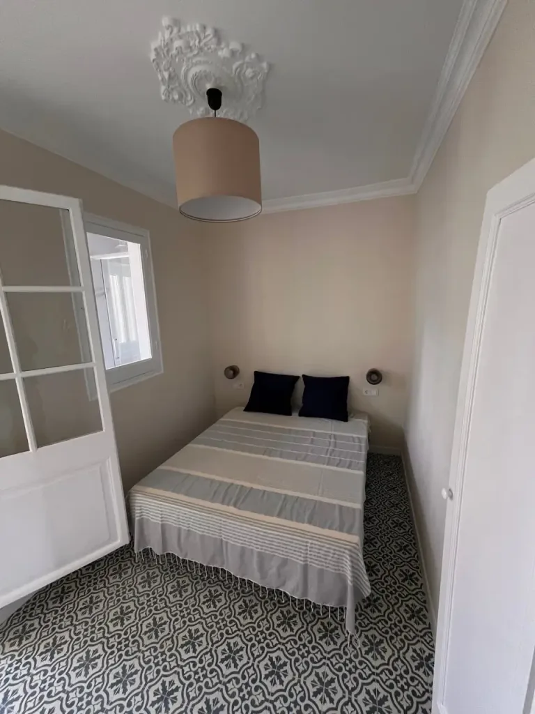habitación sencilla con cama doble y lámpara colgante beige