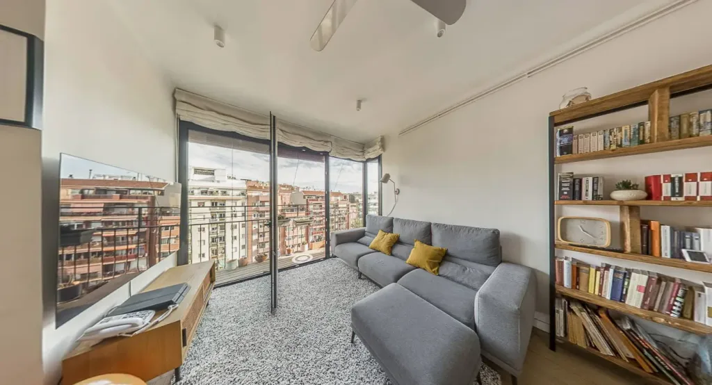 sala con vistas a la ciudad sofá gris almohadones amarillos y estantería llena