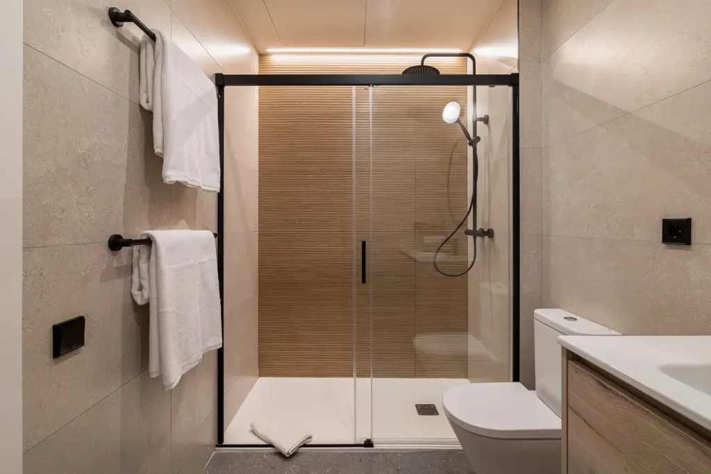Bano moderno con ducha de cristal y accesorios negros