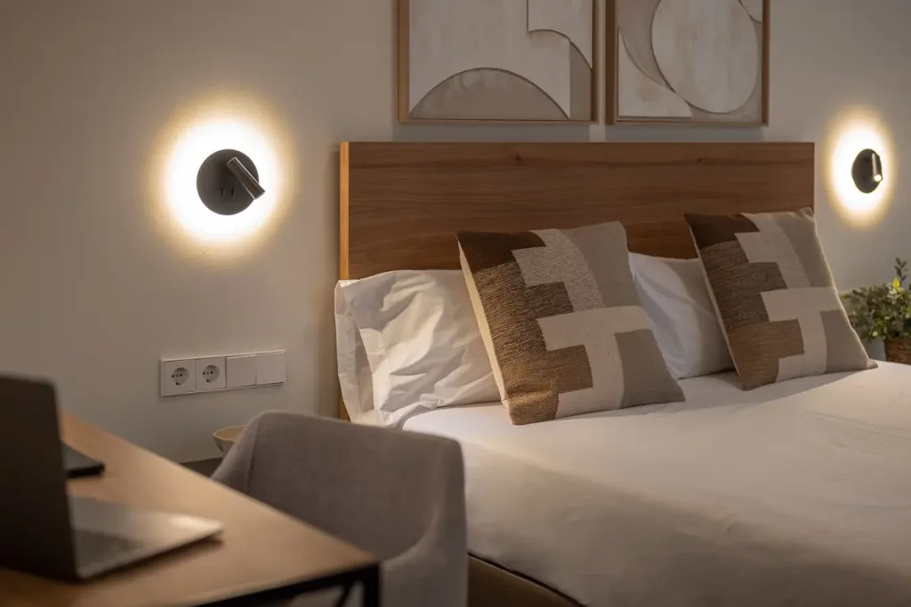 Cálida habitación con cama doble y lámparas de pared circulares