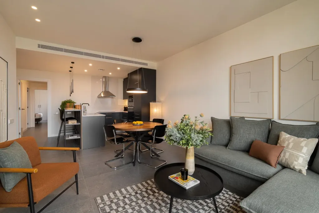 Cocina abierta a sala de estar con detalles en negro y comedor con sillas de diseño