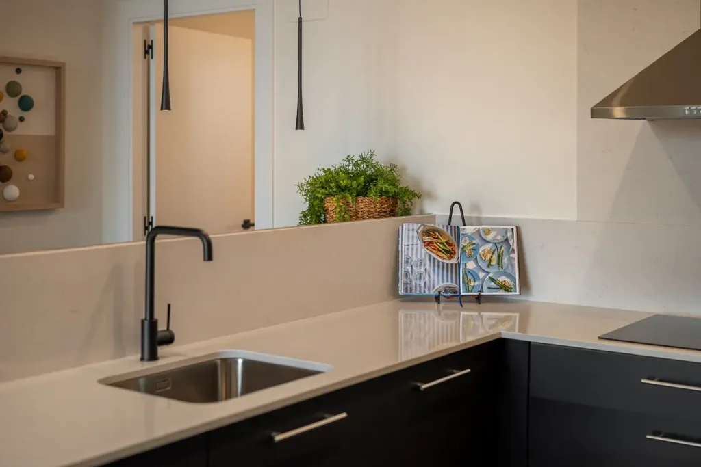 Elegante cocina moderna con encimeras blancas y grifo negro de diseño