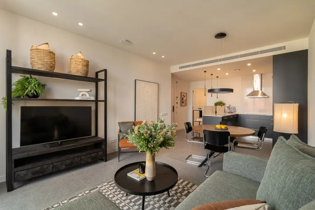 Vista amplia de una moderna sala de estar con sofá gris y cocina al fondo