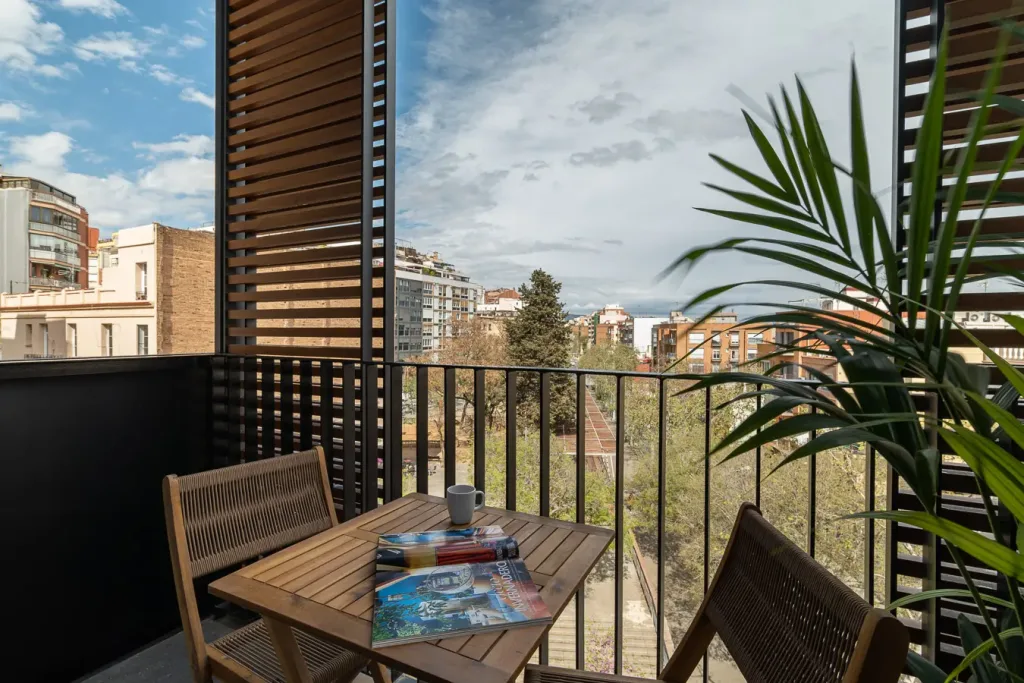 Vista de un balcon con mesa de madera y vista urbana