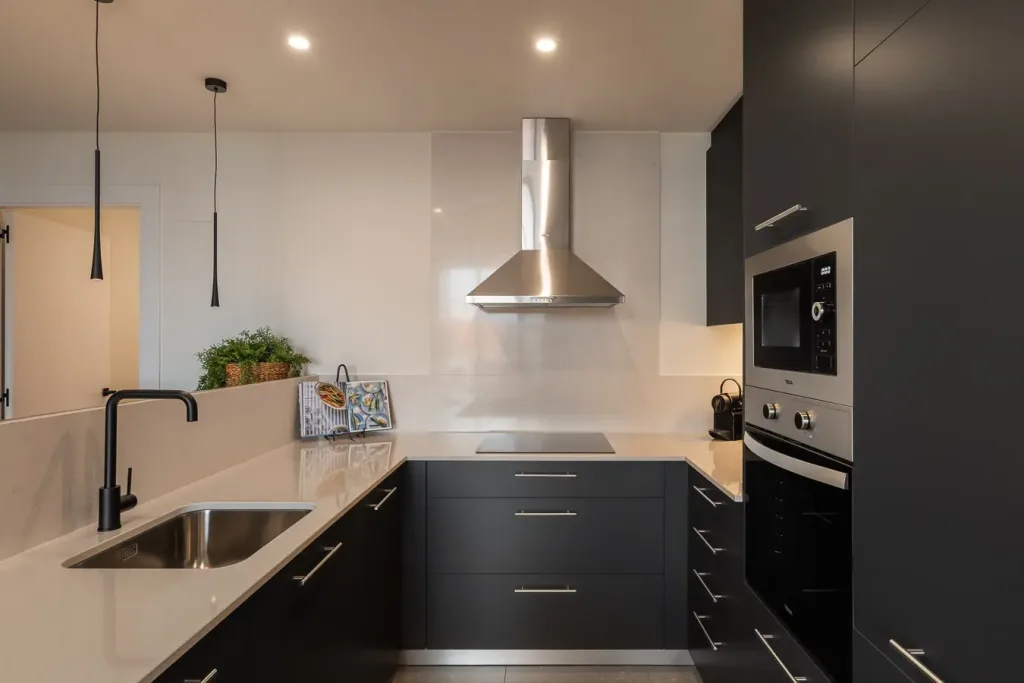 detalle de cocina con extractor de acero inoxidable y encimeras de piedra blanca