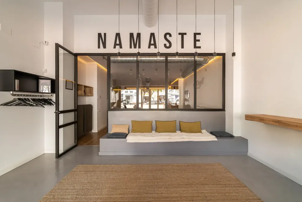 Área de espera con cojines y letrero Namaste en la pared