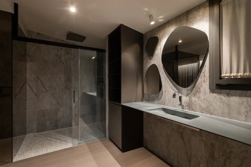 baño moderno con ducha de vidrio y mosaico de piedras