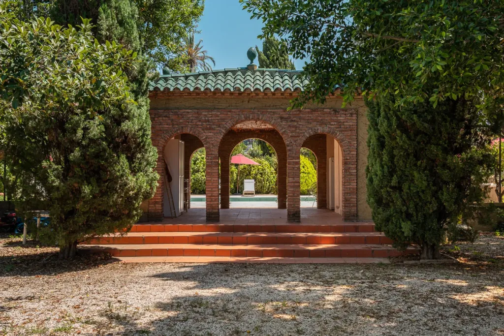 cabaña rústica con arcos y vegetación alrededor