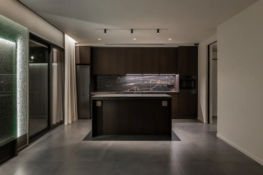 cocina moderna con isla de mármol oscuro y luz suave