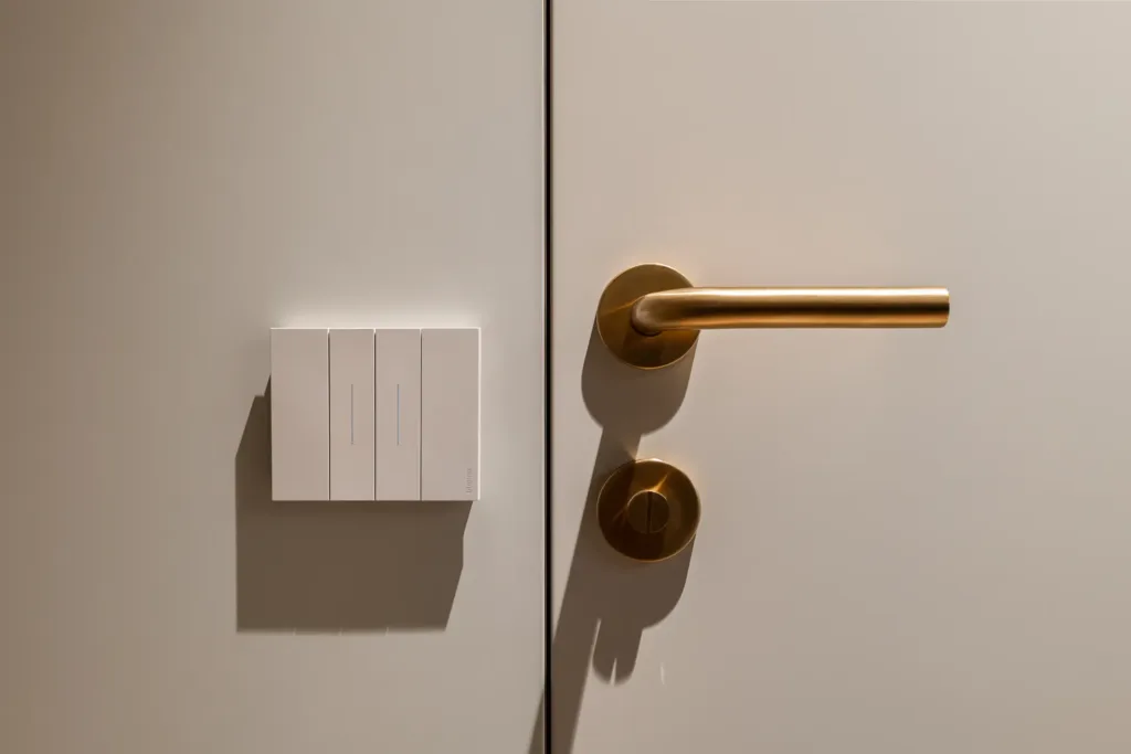 interruptores modernos y manilla de puerta dorada en pared minimalista