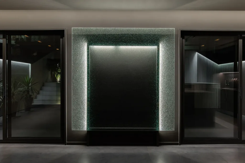 pared decorativa iluminada con cristal texturizado y marco metálico