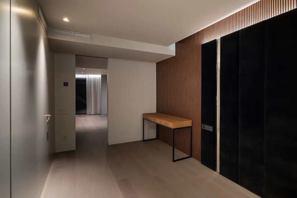 pasillo minimalista con luz suave y pared de madera y panel negro