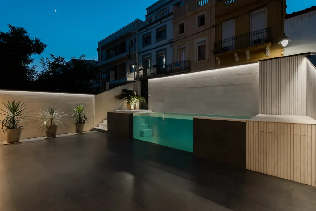piscina urbana con iluminación nocturna y plantas en macetas