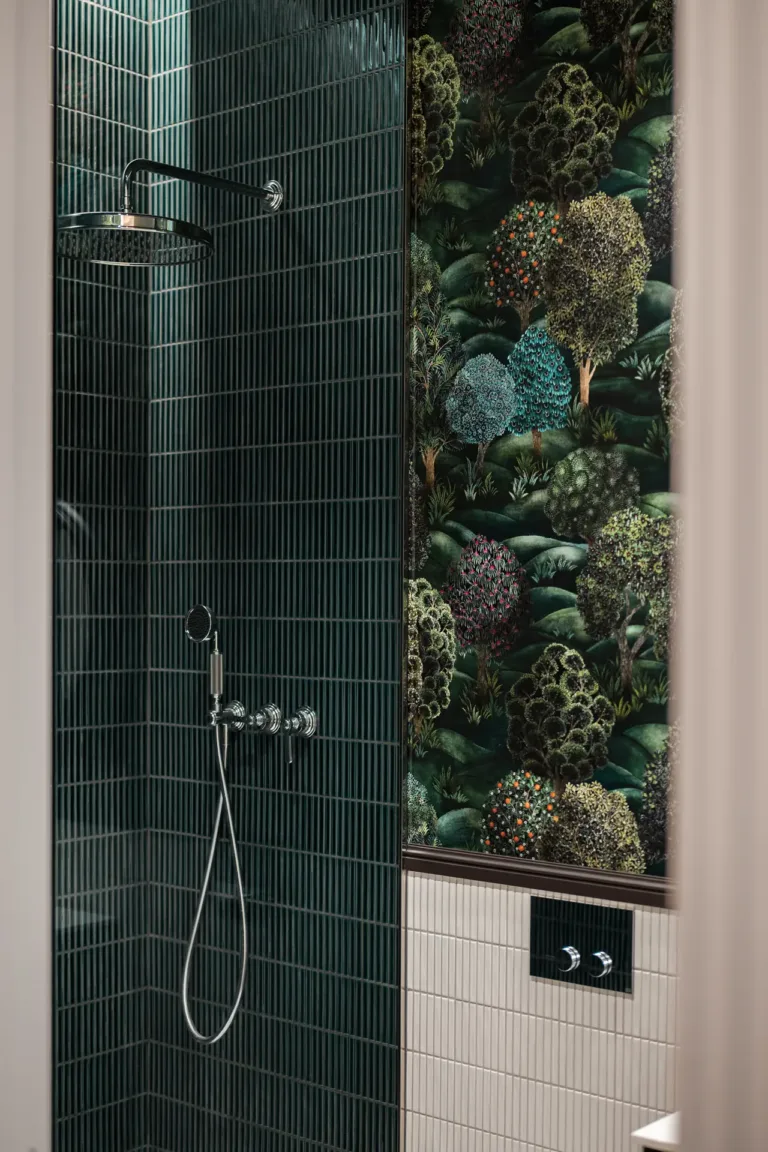 ducha con azulejos verdes y pared con diseño temático