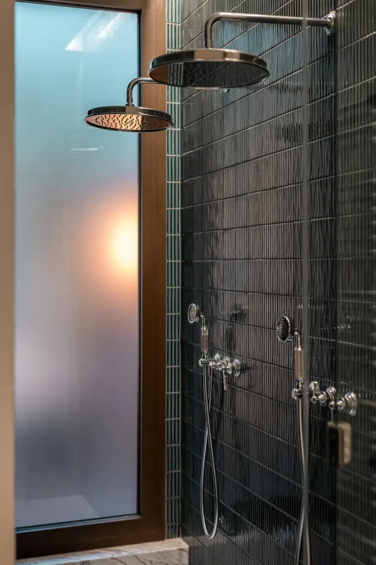 ducha de diseño con azulejos oscuros y detalles cromados