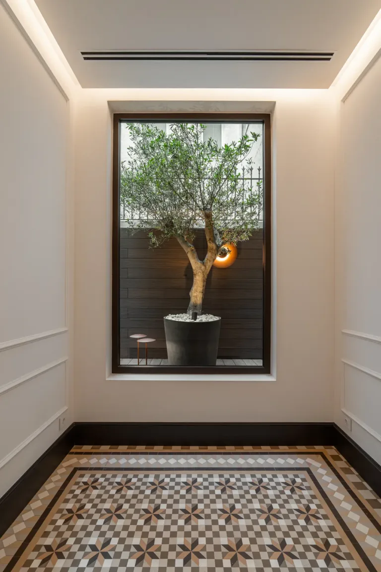 ventana con vista a un árbol decorativo y piso de mosaico