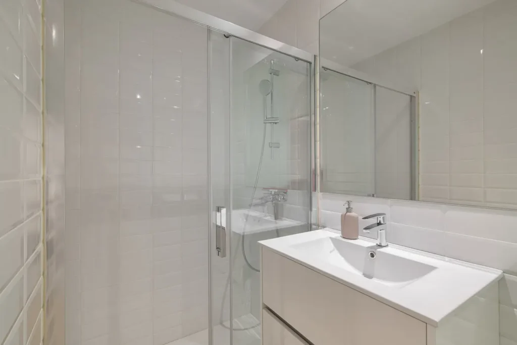 bano moderno con ducha y azulejos blancos