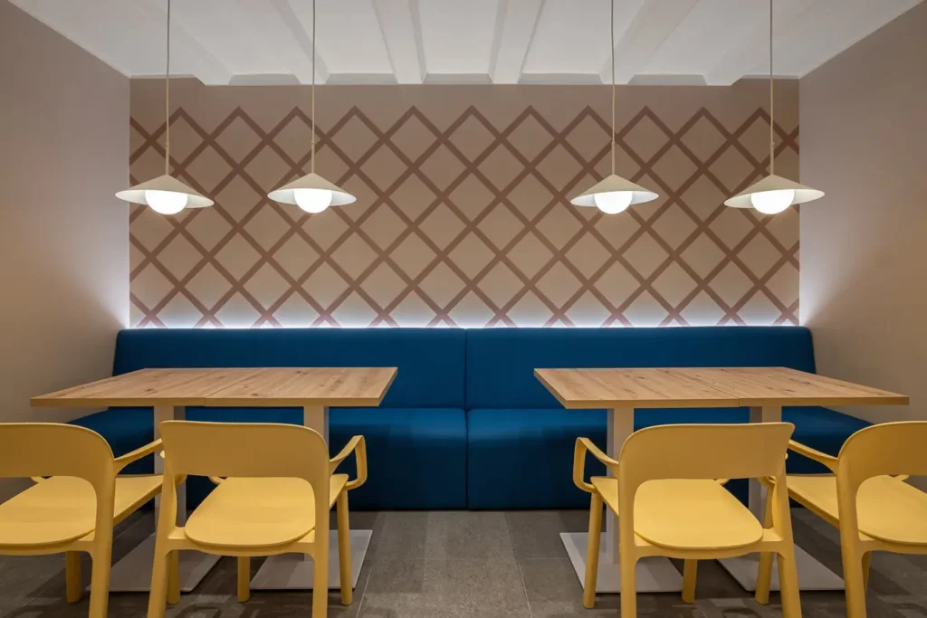 area de mesas con banqueta azul y pared con patron geometrico