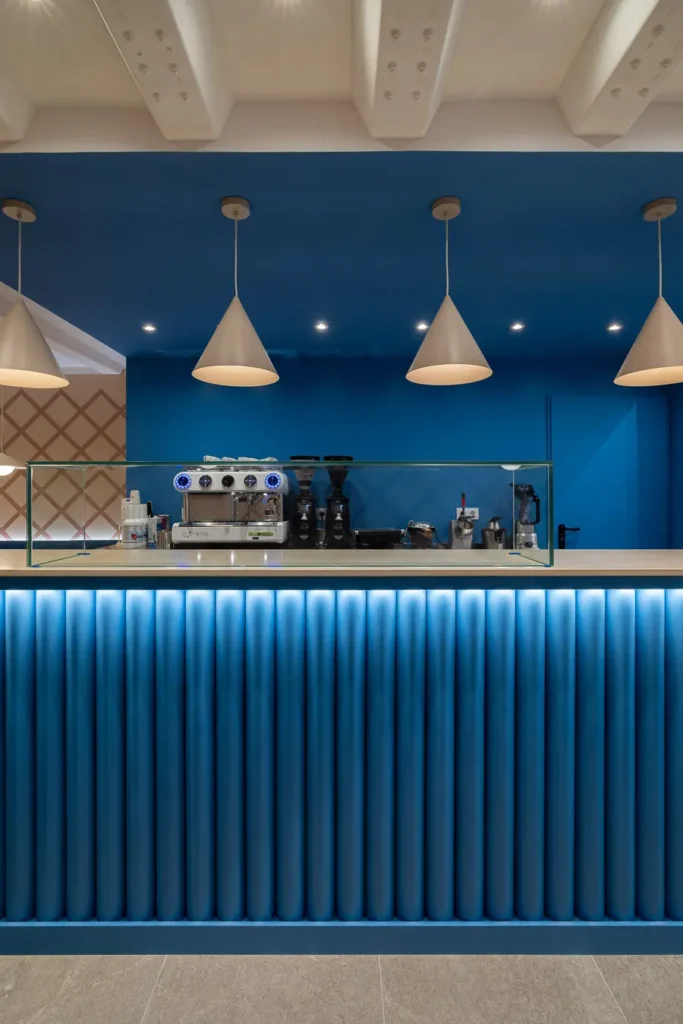 barra de cafe en tono azul con lamparas conicas colgantes