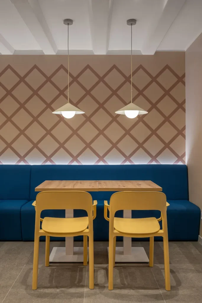 mesa con sillas amarillas y sofa azul con pared de diseno
