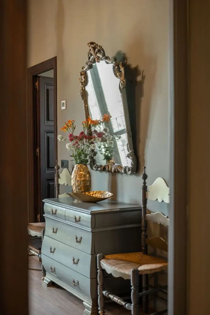 cómoda vintage verde con espejo ornamentado y jarrón con flores