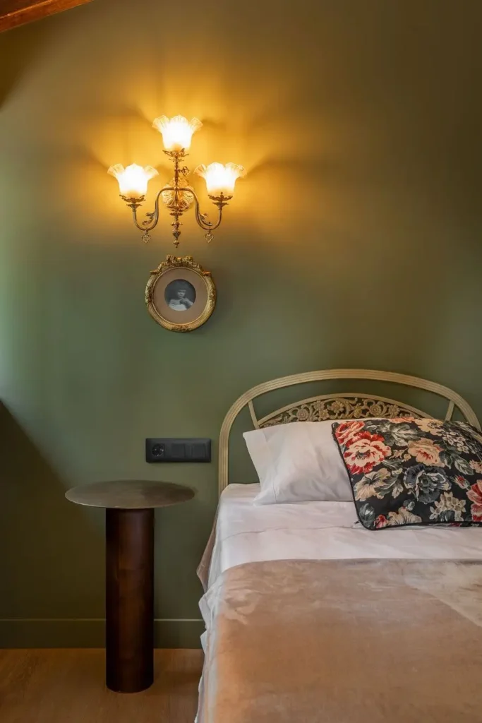 detalle de cama con cojin floral y lampara de pared