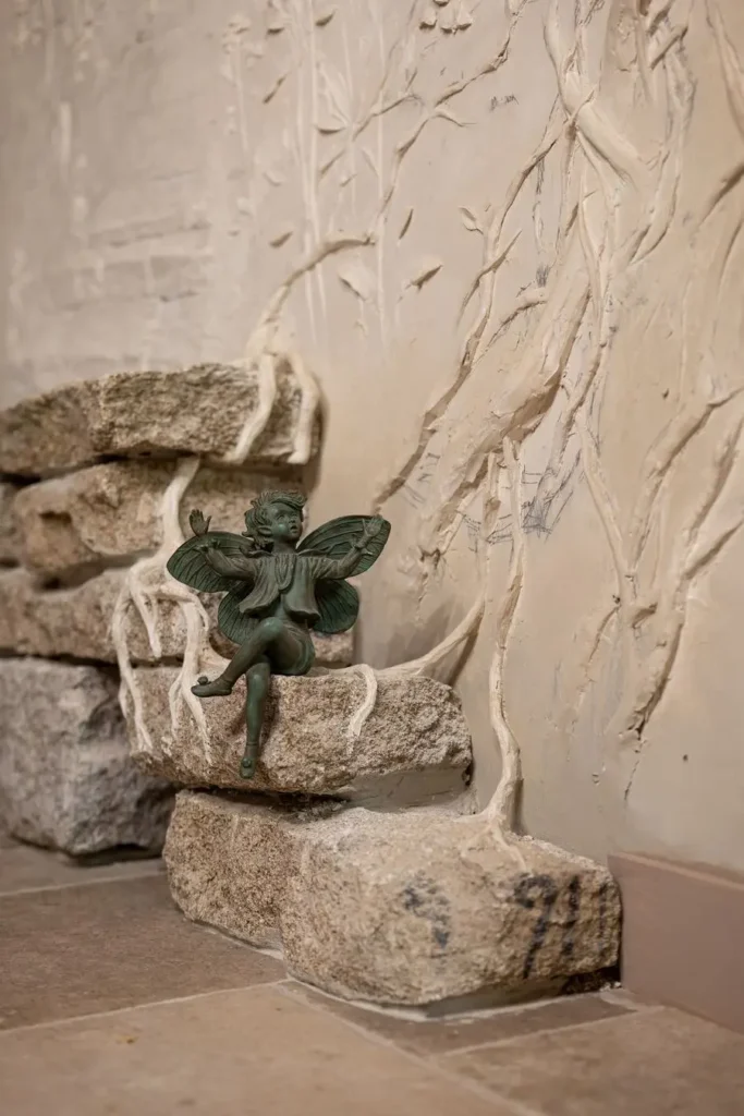 escultura de hada sobre muro de piedra y relieve
