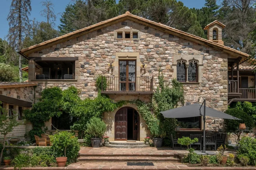 fachada principal de casa de piedra con vegetacion