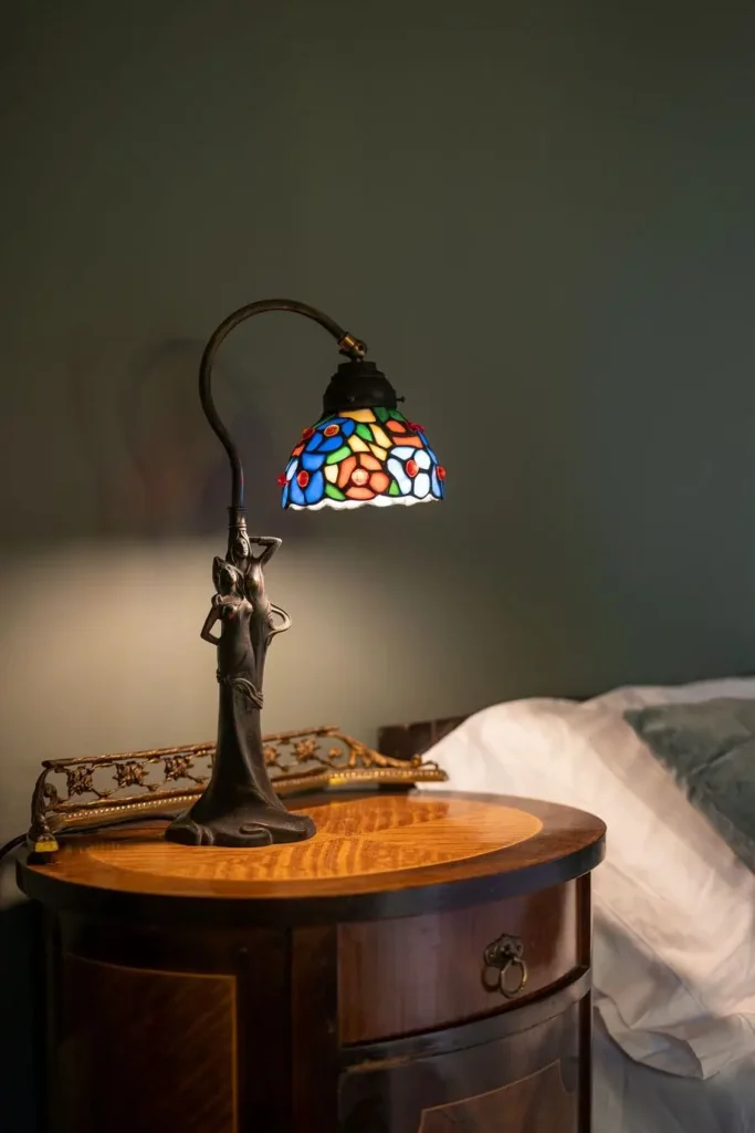 lámpara de mesa con pantalla de vidrieras de colores sobre mesita antigua