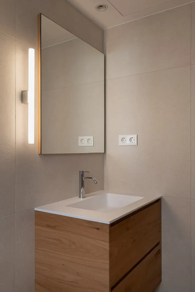 lavabo con mueble de madera espejo y aplique vertical