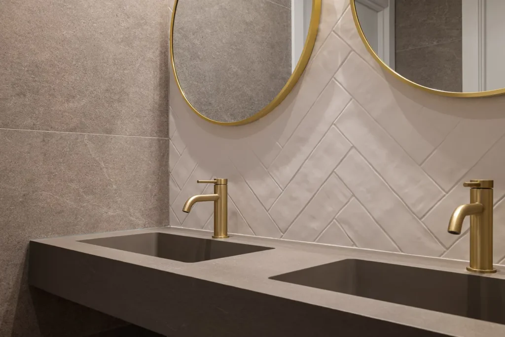 lavabo doble con espejos circulares y griferia dorada