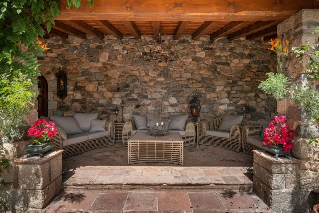 terraza rustica con muebles de mimbre y pared de piedra