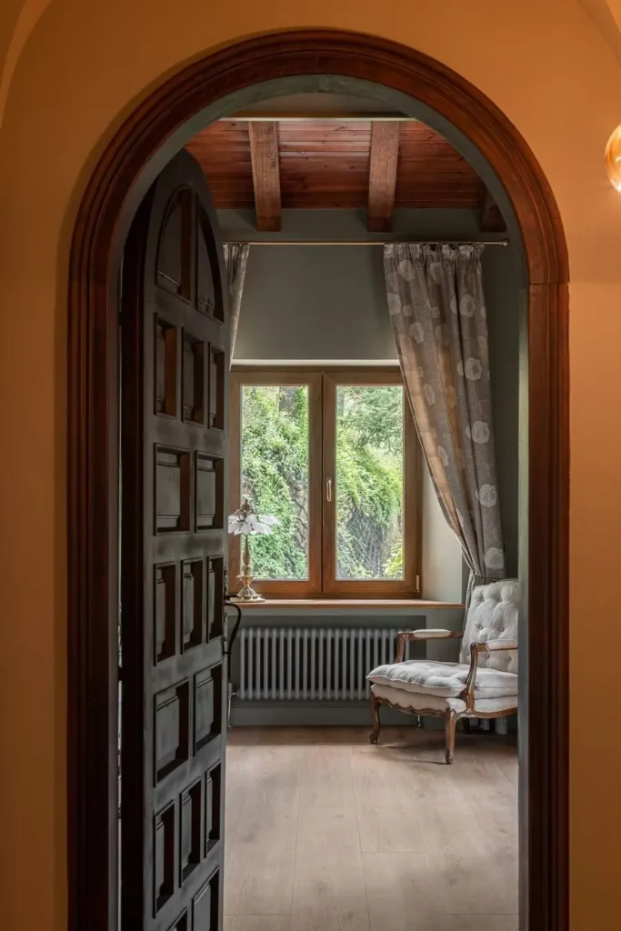 vista a traves de arco hacia salon con sillon y ventana