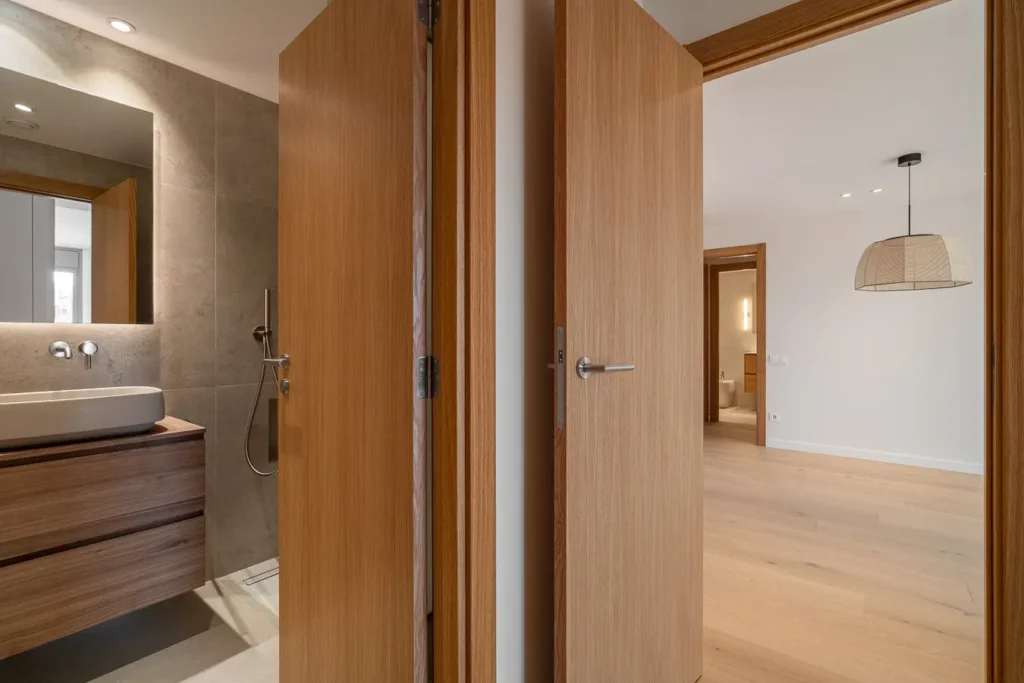 vista de bano y puertas de madera abiertas a dormitorio
