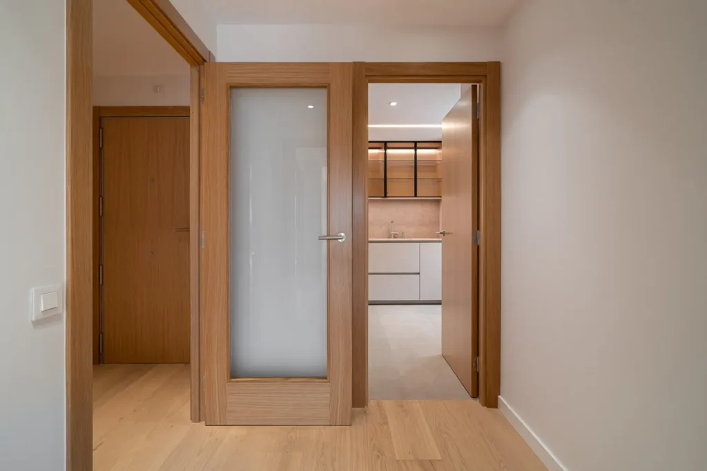 vista del pasillo hacia la cocina con puertas de madera y cristal