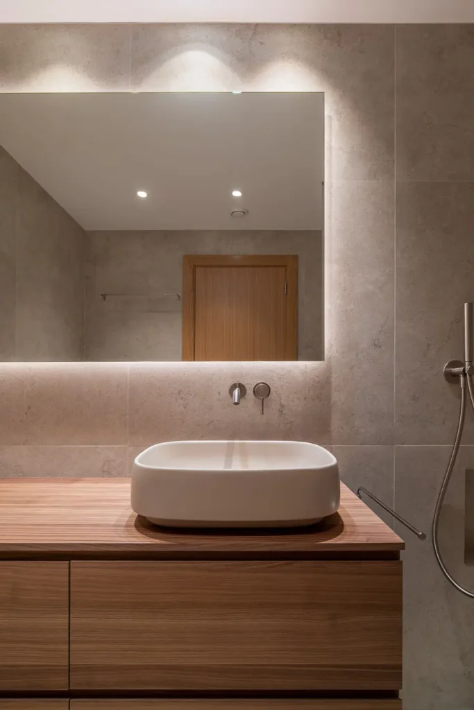 vista frontal de lavabo con espejo iluminado y revestimiento de piedra