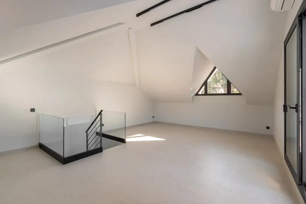 atico vacio con techos inclinados y ventana triangular