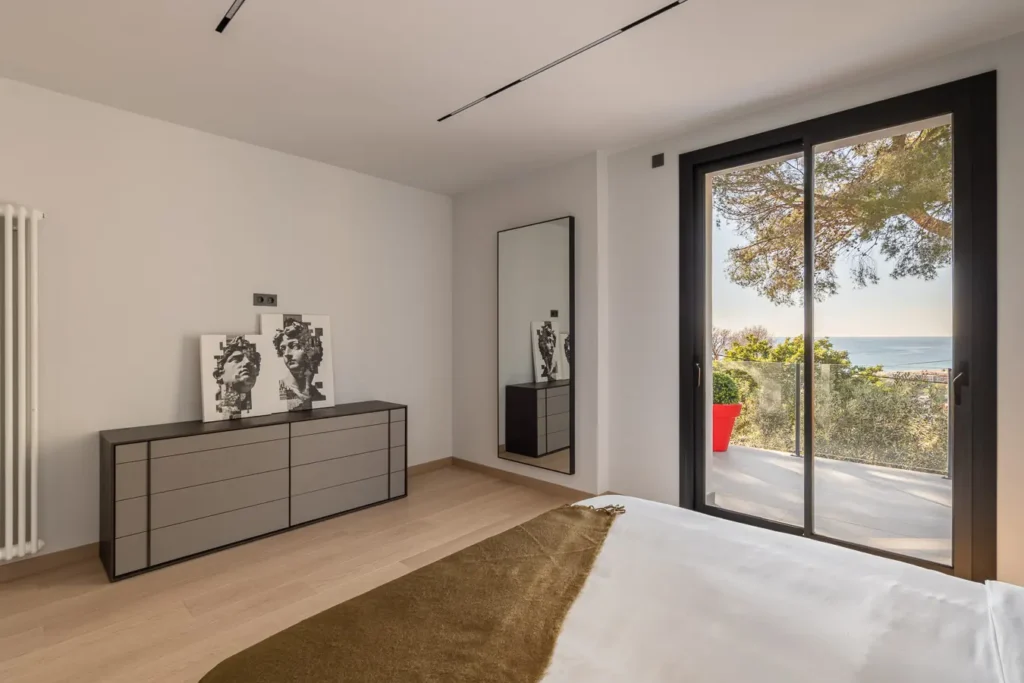 dormitorio con comoda espejo alto y salida a terraza con vistas al mar