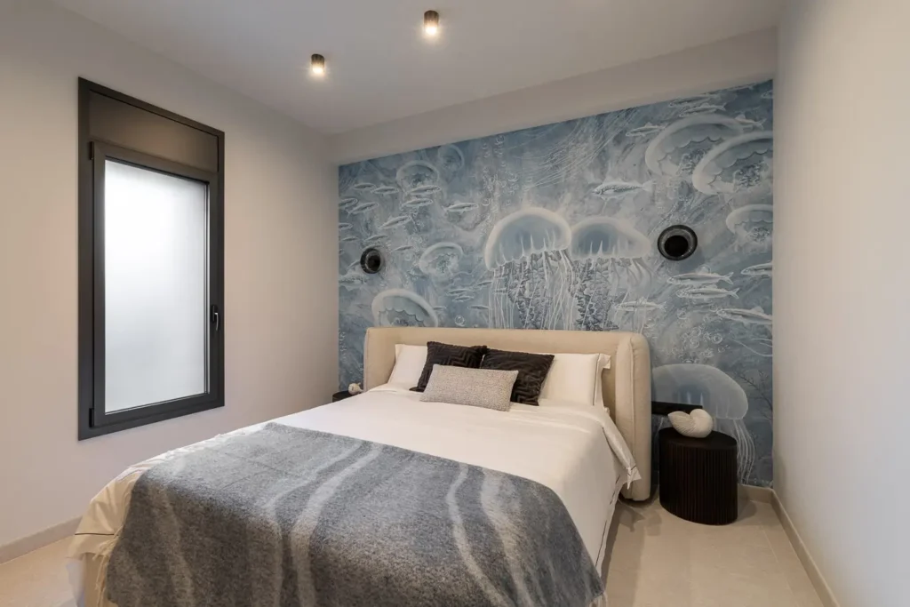 dormitorio con mural de medusas azules y cama doble con manta gris
